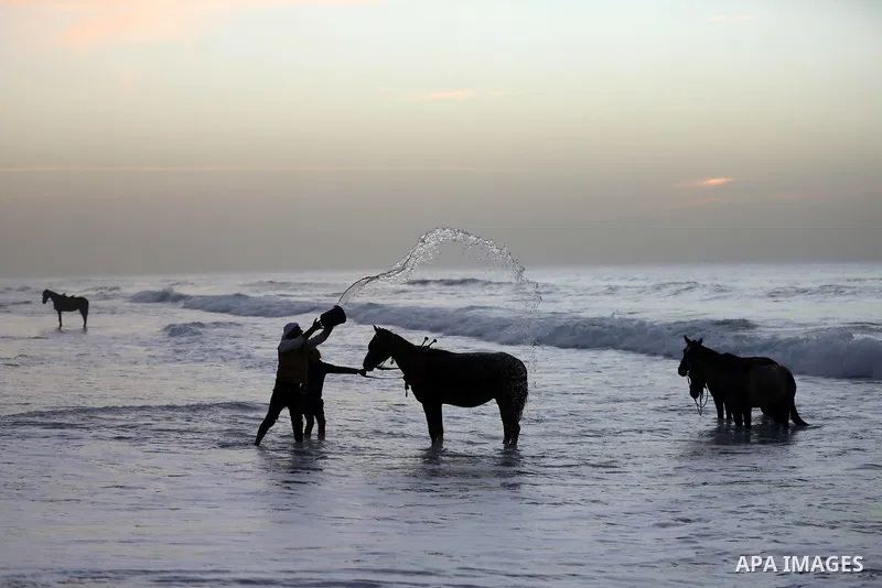 Palestinians enjoy their time during sunset along a beach by the Mediterranean Sea in Gaza City on December 10, 2021. Photo by Ashraf Amra