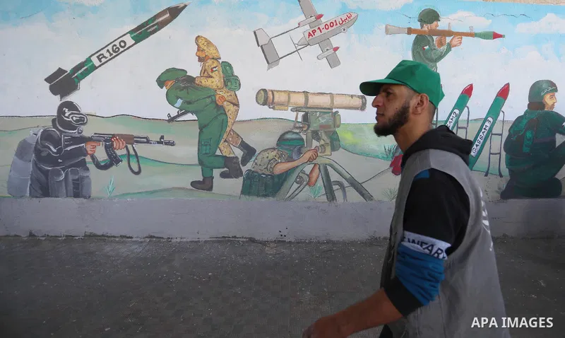 Palestinian students walk past a mural marking the 34th anniversary of the founding of the Hamas movement, in Khan Younis in the southern of Gaza strip on December 11, 2021. Photo by Ashraf Amra