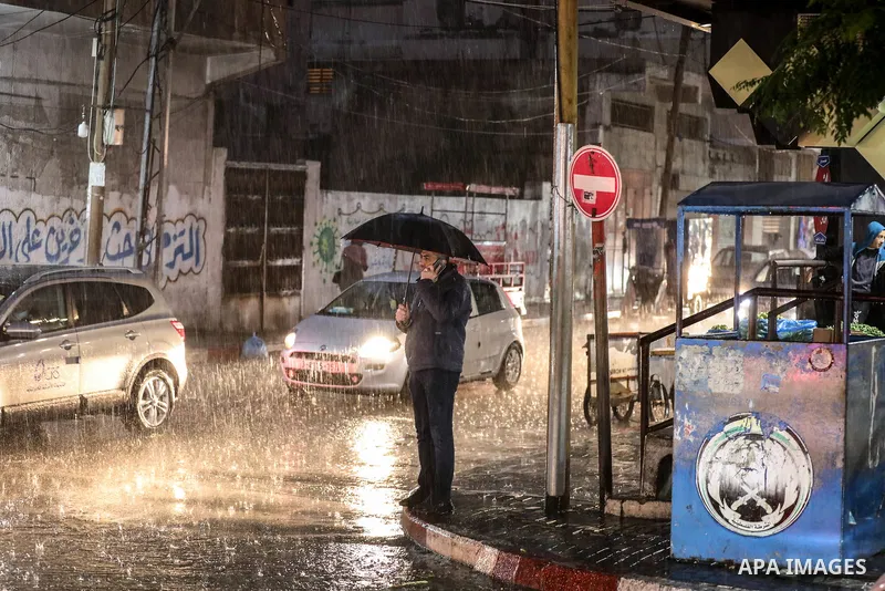 Palestinians walk at a flooded street on a cold, rainy night, in Gaza city on December 22, 2021. Photo by Atia Darwish