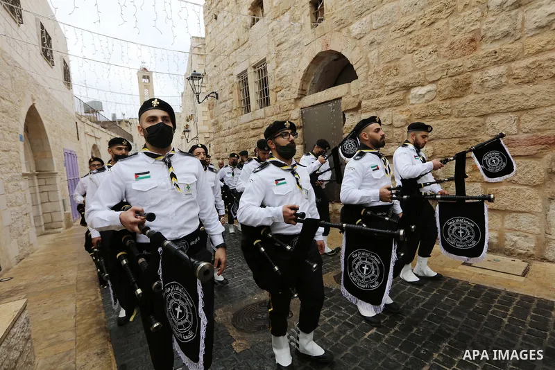 Palestinian scouts parade outside the Church of the Nativity, revered as the site of Jesus Christ's birth, during Christmas celebrations in the biblical city of Bethlehem in the West Bank, on December 24, 2021. Photo by...