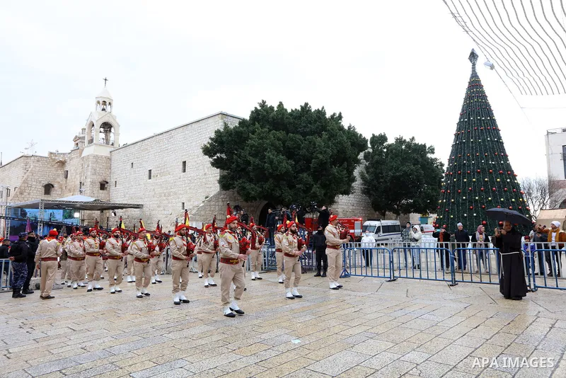 Palestinian scouts parade outside the Church of the Nativity, revered as the site of Jesus Christ's birth, during Christmas celebrations in the biblical city of Bethlehem in the West Bank, on December 24, 2021. Photo by...