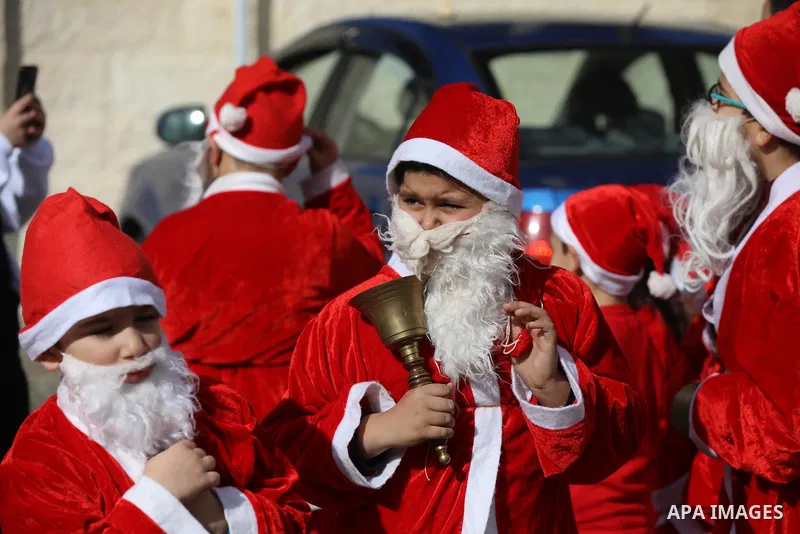 Palestinian Christian children dressed as Santa Claus, walk outside the Church of Saint Porphyrios during Christmas celebrations in Gaza City, on December 24, 2021. Photo by Ashraf Amra