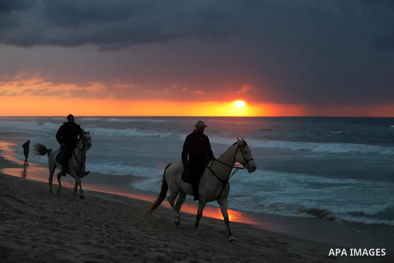 Palestinians enjoy their time on the beach of Gaza sea during sunset on December 24, 2021. The beach is one of the few open public spaces in this densely populated city. Photo by Ashraf Amra