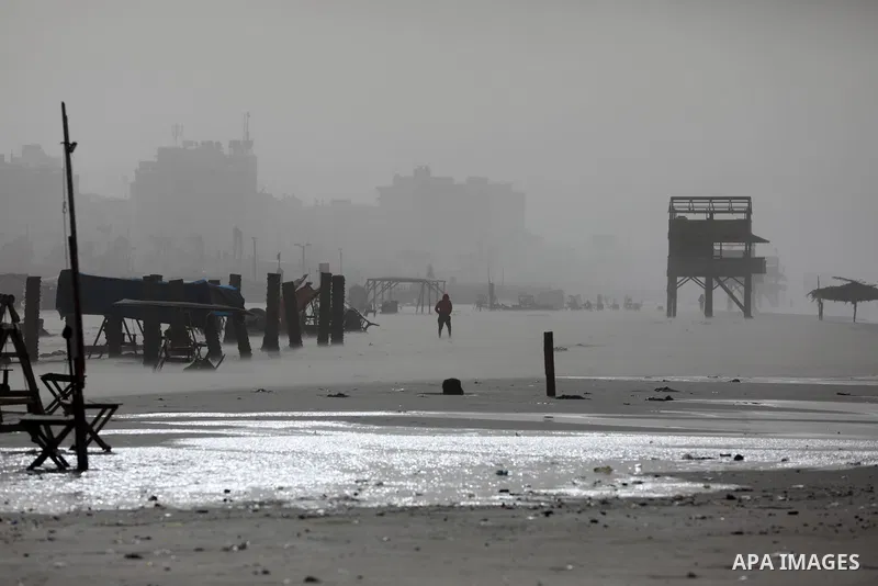 Palestinians walk along a beach by the Mediterranean Sea in Gaza City during stormy weather on December 8, 2021. Photo by Ashraf Amra