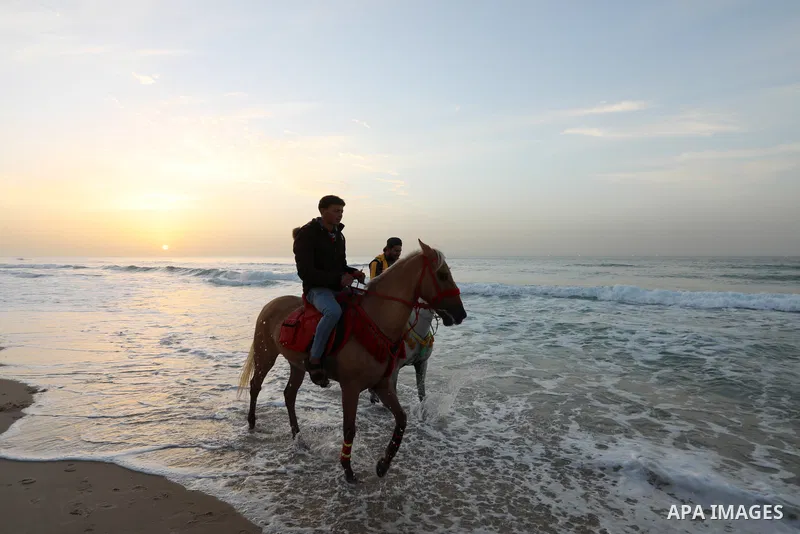 Palestinians enjoy their time during sunset along a beach by the Mediterranean Sea in Gaza City on December 10, 2021. Photo by Ashraf Amra