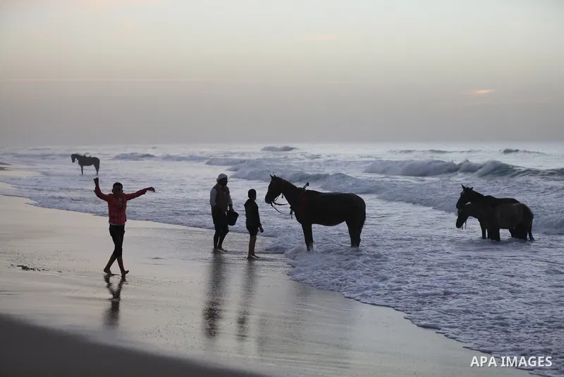Palestinians enjoy their time during sunset along a beach by the Mediterranean Sea in Gaza City on December 10, 2021. Photo by Ashraf Amra