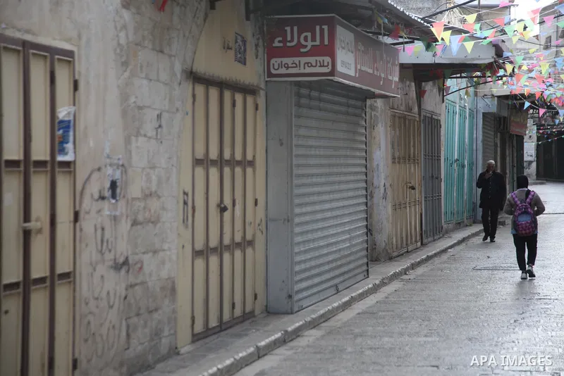 A Palestinian man walks past shuttered stores in the West Bank city of Nablus, on December 13, 2021. Israeli forces Monday killed a Palestinian youth and injured two others during a night military raid in the area of Ras...