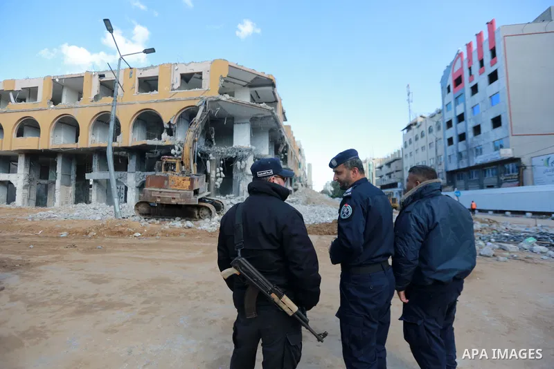 Palestinian workers remove the rubbles of al-Jawhara tower which was hit by Israeli strikes during the recent 11-day conflict between Israel and Hamas on May, in Gaza city on December 19, 2021. Photo by Bashar Taleb