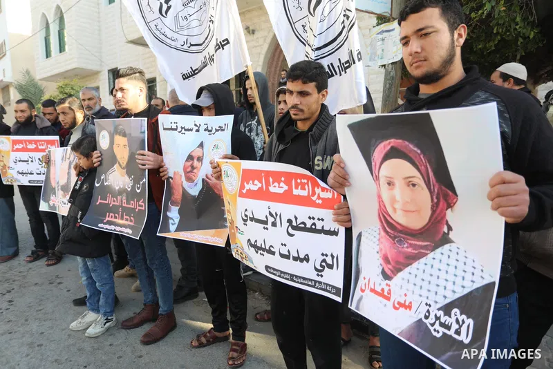 Palestinians hold placards during a protest in solidarity with female prisoners at Israeli jails, in Deir Al Balah in the center of Gaza strip on December 21, 2021. Photo by Ashraf Amra