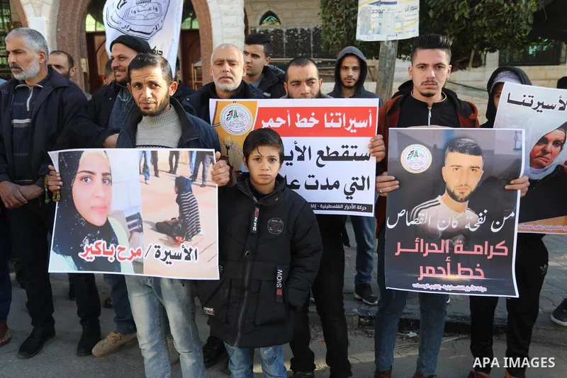 Palestinians hold placards during a protest in solidarity with female prisoners at Israeli jails, in Deir Al Balah in the center of Gaza strip on December 21, 2021. Photo by Ashraf Amra
