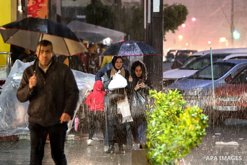 Palestinians walk at a flooded street on a cold, rainy night, in Gaza city on December 22, 2021. Photo by Atia Darwish