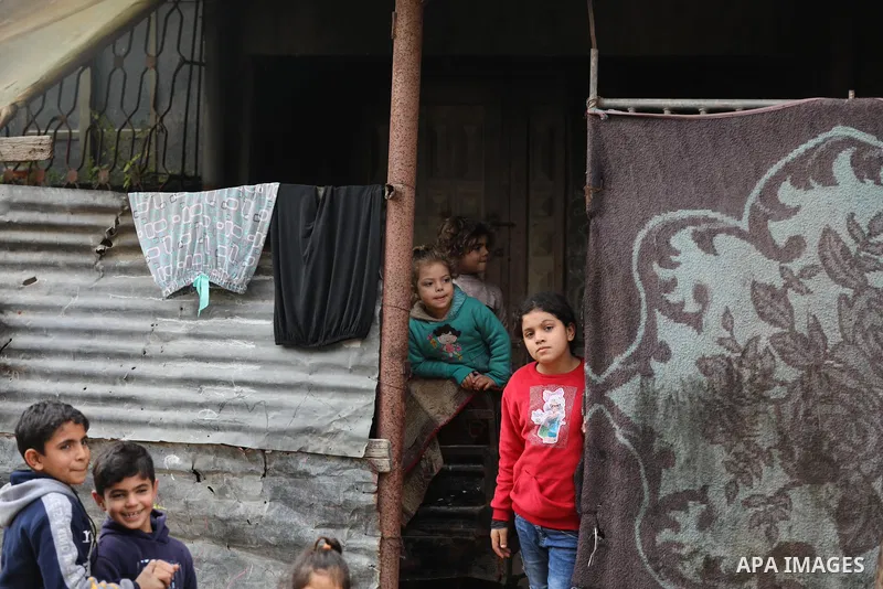 Palestinians sit outside their home on a cold, rainy day in Beit Lahia in the northern Gaza Strip December 23, 2021. Photo by Ashraf Amra