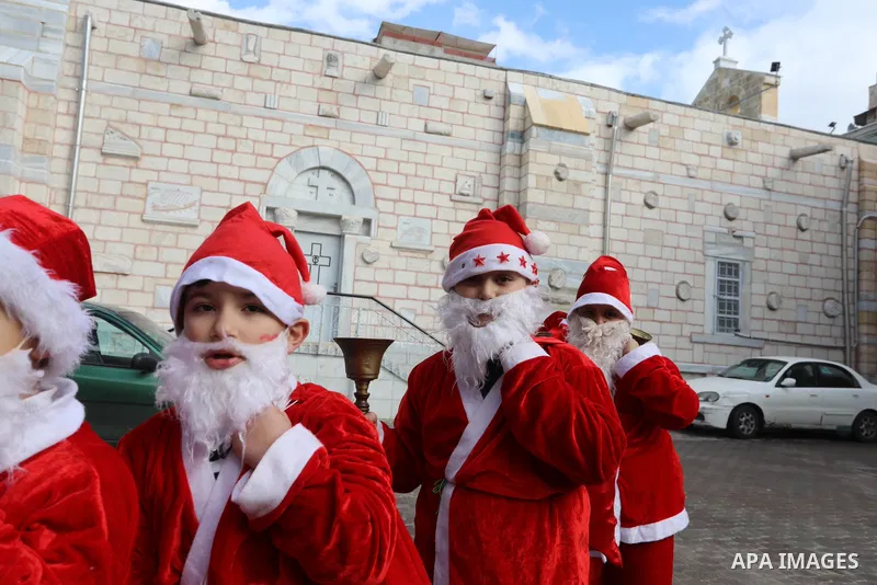 Palestinian Christian children dressed as Santa Claus, walk outside the Church of Saint Porphyrios during Christmas celebrations in Gaza City, on December 24, 2021. Photo by Ashraf Amra