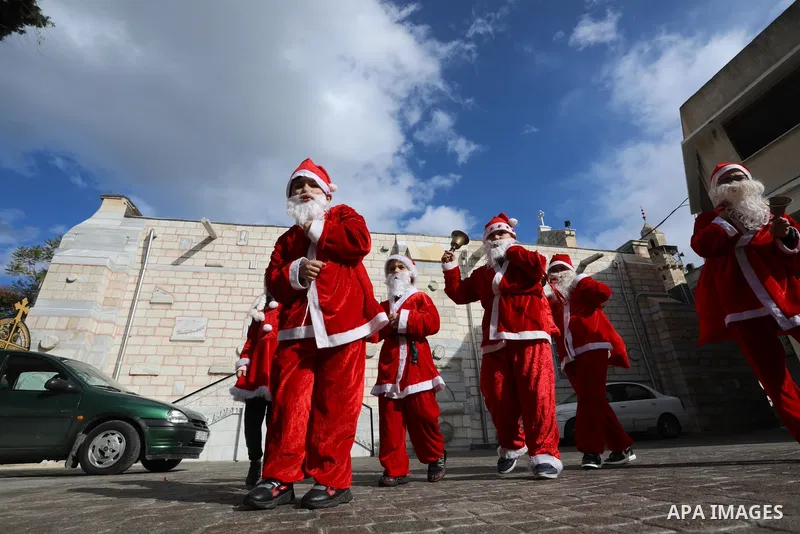 Palestinian Christian children dressed as Santa Claus, walk outside the Church of Saint Porphyrios during Christmas celebrations in Gaza City, on December 24, 2021. Photo by Ashraf Amra