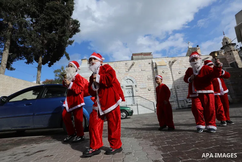Palestinian Christian children dressed as Santa Claus, walk outside the Church of Saint Porphyrios during Christmas celebrations in Gaza City, on December 24, 2021. Photo by Ashraf Amra