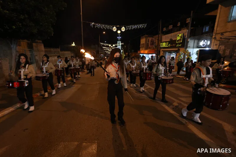 Palestinians light candles as they take part in a march during Christmas celebrations in Beit Sahour in West Bank City of Bethlehem on December 25, 2021. Photo by Ahmad Tayem