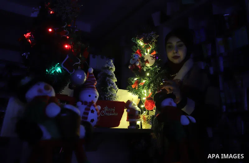 Palestinian girl Doaa Magdi hangs Christmas decoration during Christmas celebrations, at her shop in Gaza city on December 26, 2021. Christmas is an annual festival commemorating the birth of Jesus Christ. Photo by Omar...