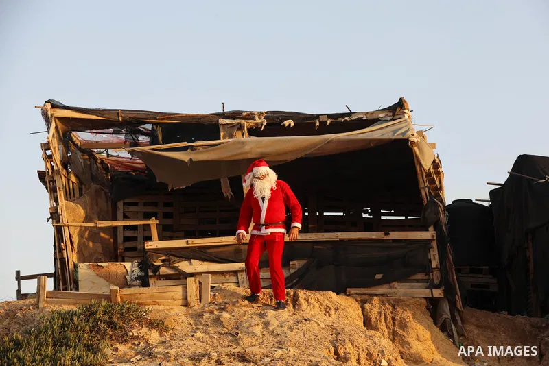 A Palestinian Christian man dressed as Santa Claus walks along beach of in Beit Lahia sea in the northern of Gaza strip, on December 27, 2021. Photo by Ashraf Amra