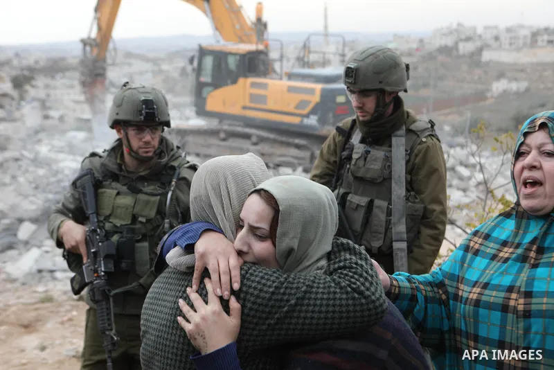 A Palestinian woman reacts while an Israeli machinery demolishes her under-construction house, in the West Bank city of Hebron, on December 28, 2021. They told WAFA correspondent that a sizable military unit escorted a b...