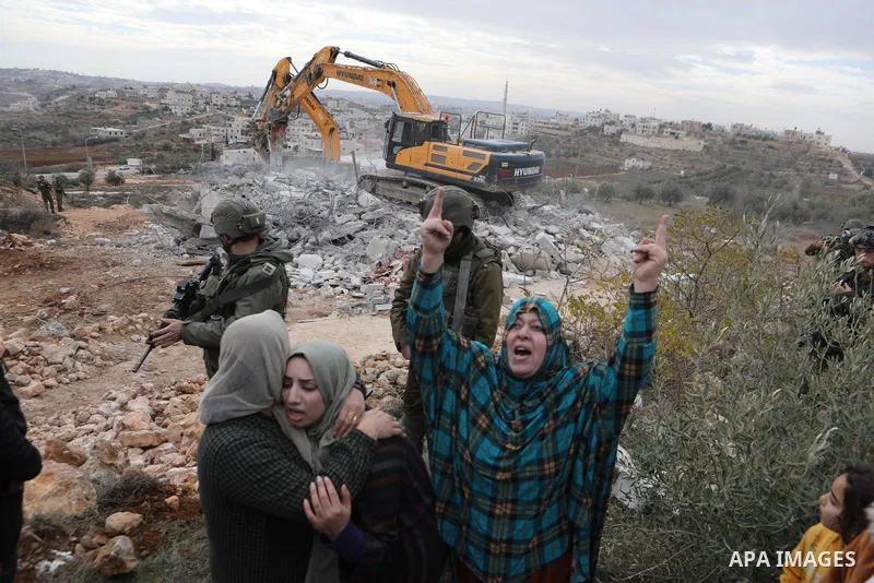 Palestinian women react while an Israeli machinery demolishes thier under-construction house, in the West Bank city of Hebron, on December 28, 2021. They told WAFA correspondent that a sizable military unit escorted a bu...
