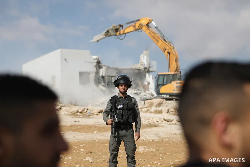 Israeli security forces stand guard as a bulldozer demolishes a Palestinian home in Jawaya village near Yatta in area "C", of the southern part of the West Bank town of Hebron, on October 3, 2021, which according to Isra...