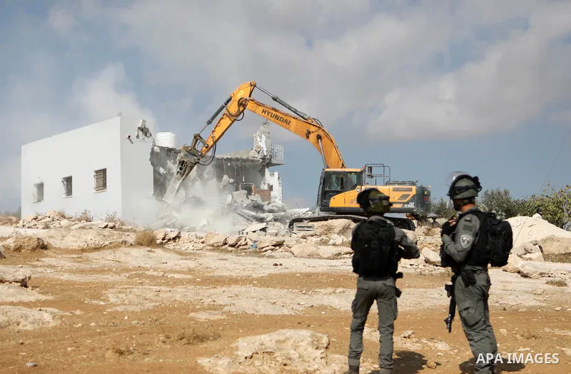 Israeli security forces stand guard as a bulldozer demolishes a Palestinian home in Jawaya village near Yatta in area "C", of the southern part of the West Bank town of Hebron, on October 3, 2021, which according to Isra...