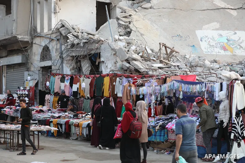 Palestinian street vendors sell clothes near the rubble of al-Shuruq tower in Gaza City's al-Rimal neighbourhood which was targeted by Israeli strikes during the recent confrontations between Hamas and Israel, on Novembe...