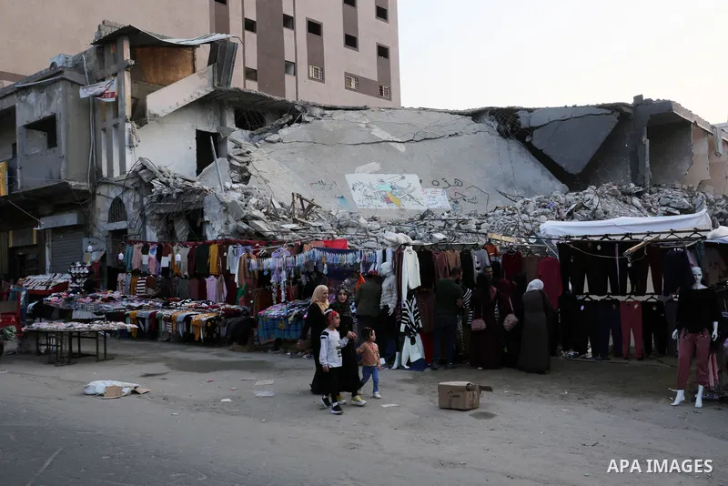 Palestinian street vendors sell clothes near the rubble of al-Shuruq tower in Gaza City's al-Rimal neighbourhood which was targeted by Israeli strikes during the recent confrontations between Hamas and Israel, on Novembe...