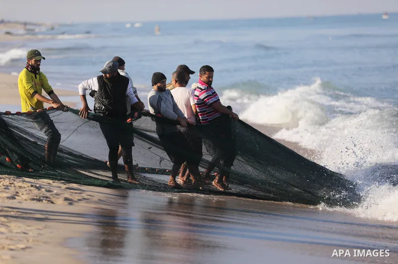 Palestinian fishermen work on the shore of the Mediterranean Sea, in Gaza city, on November 27, 2021. The Israeli authorities released the two detained fishermen at Erez crossing, north of Gaza, and seized their boat. Is...