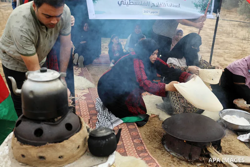 Volunteers prepare traditional Palestinian food during an initiative to help Palestinian farmers and families to pick olives during the harvest season, in Khan Younis in the southern of Gaza Strip on October 3, 2021. Oli...