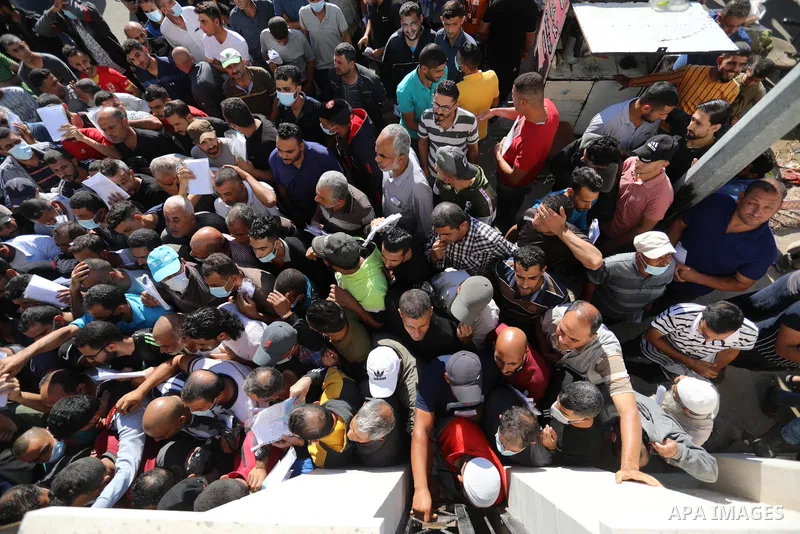 Palestinian citizens gather to apply for work permits in Israel territories in front of the Gaza Chamber of Commerce and Industry ​headquarters to register in order to work inside the Israel territories, in Deir al-Balah...
