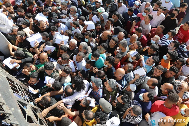 Palestinian citizens gather to apply for work permits in Israel territories in front of the Gaza Chamber of Commerce and Industry ​headquarters to register in order to work inside the Israel territories, in Deir al-Balah...
