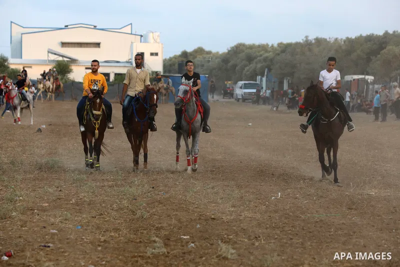 Palestinians ride horses and camels during a local race, in Nuseirat, in the center of Gaza strip on October 8, 2021. Breeders of Arabian horses in Gaza have been struggling to secure the necessary medicines and vaccinat...