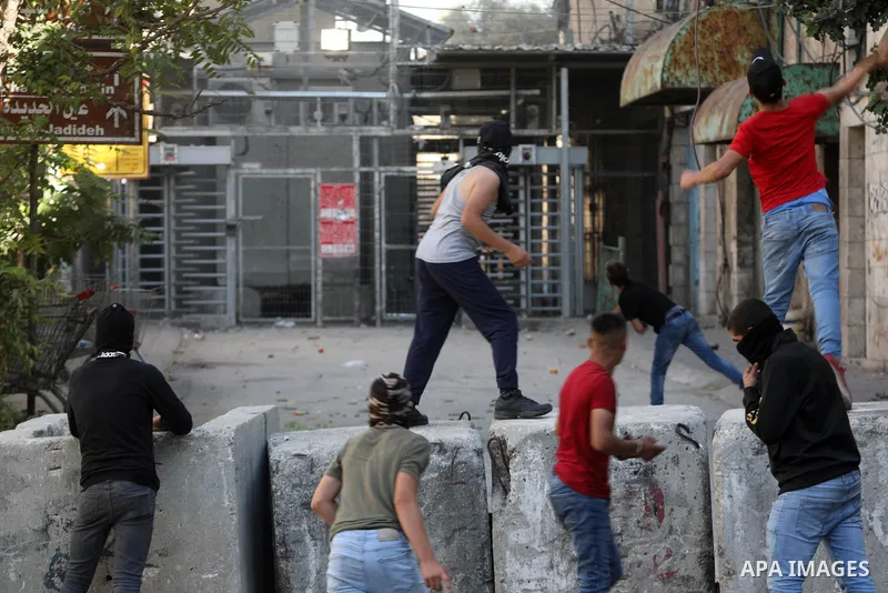 Palestinian protesters hurl stones towards Israeli troops during clashes in the West Bank city of Hebron, on October 8, 2021. Photo by Mamoun Wazwaz