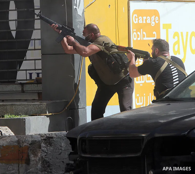 Shiite fighters from Hezbollah and Amal movements takes aim with a Kalashnikov assault rifle amidst clashes in the area of Tayouneh, in the southern suburb of the capital Beirut, on October 14, 2021. - Gunfire killed sev...
