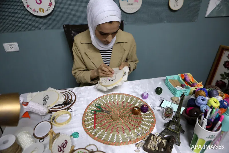 Palestinian artist Hadeel Al-Hassana 24, embroiders on fabric, at her home in the West Bank city of Hebron, on October 14, 2021. Hadeel is a graphic design graduate, and she is the owner of a project in the name of the w...