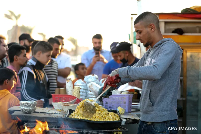 A Palestinian man grills corn on the cob at a stall on Gaza City's seaside, on October 22, 2021. Photo by Atia Darwish
