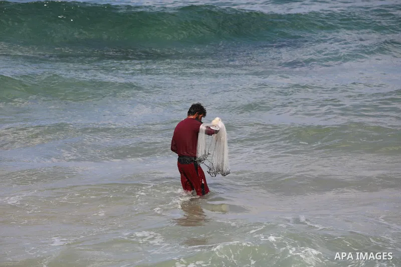 A Palestinian fisherman collects fish nets on the beach of the Mediterranean sea in Gaza City, on October 23, 2021. Fishing is a major source of revenue for the impoverished Palestinian enclave. Israel, which maintains a...