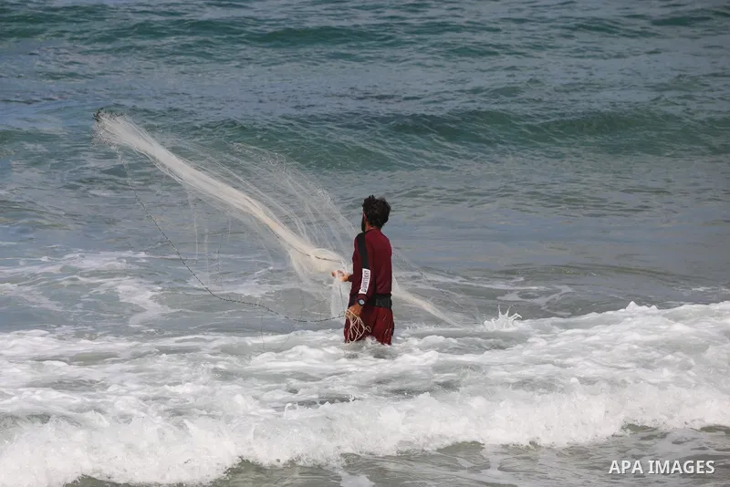 A Palestinian fisherman collects fish nets on the beach of the Mediterranean sea in Gaza City, on October 23, 2021. Fishing is a major source of revenue for the impoverished Palestinian enclave. Israel, which maintains a...