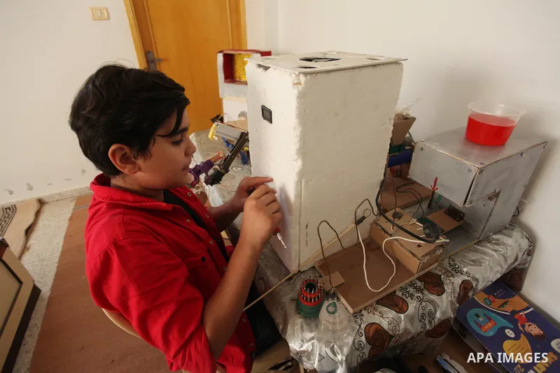 Palestinian inventor Mohammad Al-Hallaq,13, displays his small inventions at his home in Khan Yunis, in the southern Gaza Strip, on October 23, 2021. Al-Hallaq invented the robot for special needs and portable refrigerat...