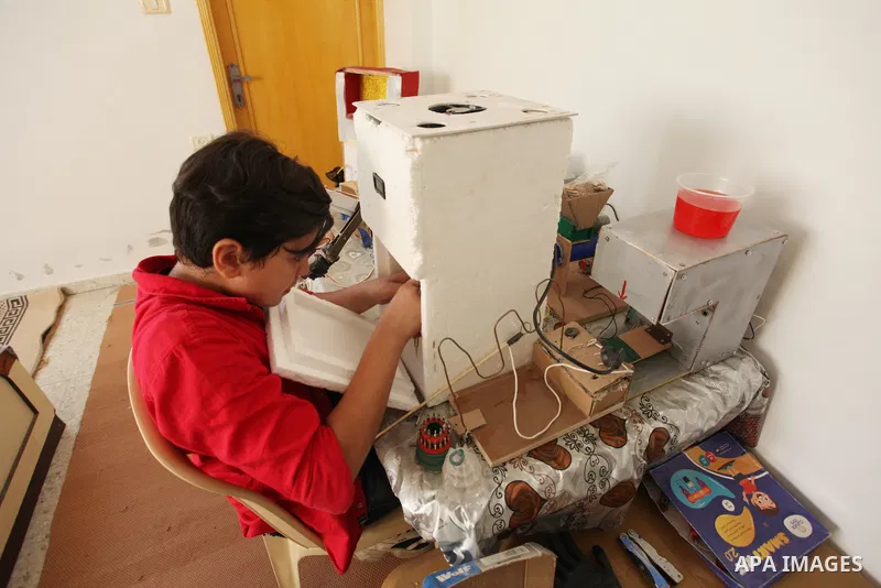Palestinian inventor Mohammad Al-Hallaq,13, displays his small inventions at his home in Khan Yunis, in the southern Gaza Strip, on October 23, 2021. Al-Hallaq invented the robot for special needs and portable refrigerat...