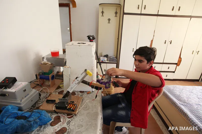 Palestinian inventor Mohammad Al-Hallaq,13, displays his small inventions at his home in Khan Yunis, in the southern Gaza Strip, on October 23, 2021. Al-Hallaq invented the robot for special needs and portable refrigerat...