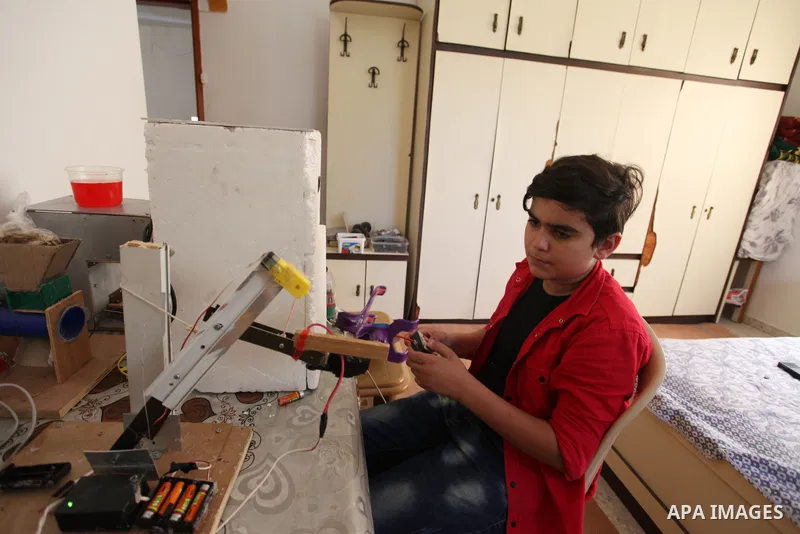 Palestinian inventor Mohammad Al-Hallaq,13, displays his small inventions at his home in Khan Yunis, in the southern Gaza Strip, on October 23, 2021. Al-Hallaq invented the robot for special needs and portable refrigerat...