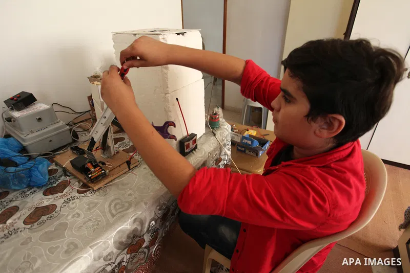 Palestinian inventor Mohammad Al-Hallaq,13, displays his small inventions at his home in Khan Yunis, in the southern Gaza Strip, on October 23, 2021. Al-Hallaq invented the robot for special needs and portable refrigerat...