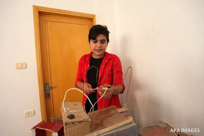 Palestinian inventor Mohammad Al-Hallaq,13, displays his small inventions at his home in Khan Yunis, in the southern Gaza Strip, on October 23, 2021. Al-Hallaq invented the robot for special needs and portable refrigerat...