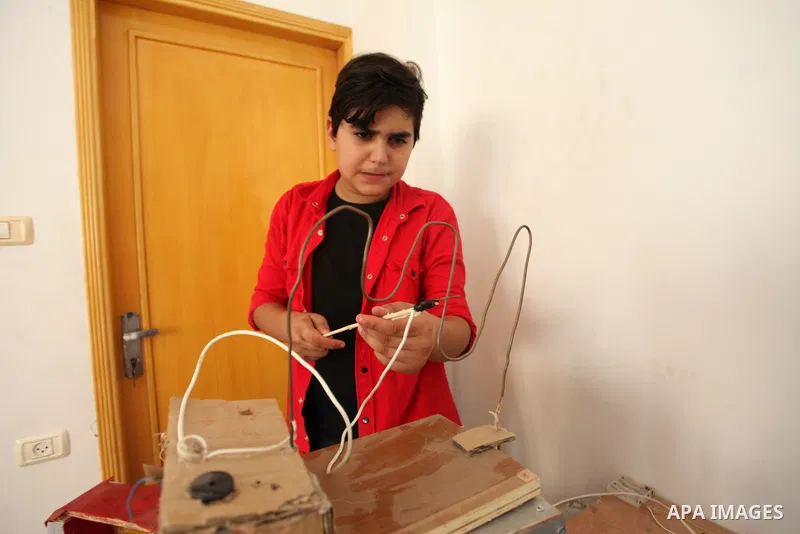 Palestinian inventor Mohammad Al-Hallaq,13, displays his small inventions at his home in Khan Yunis, in the southern Gaza Strip, on October 23, 2021. Al-Hallaq invented the robot for special needs and portable refrigerat...