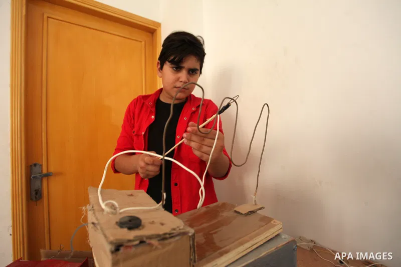 Palestinian inventor Mohammad Al-Hallaq,13, displays his small inventions at his home in Khan Yunis, in the southern Gaza Strip, on October 23, 2021. Al-Hallaq invented the robot for special needs and portable refrigerat...