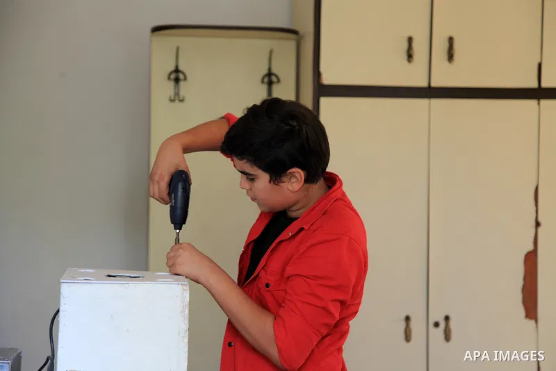 Palestinian inventor Mohammad Al-Hallaq,13, displays his small inventions at his home in Khan Yunis, in the southern Gaza Strip, on October 23, 2021. Al-Hallaq invented the robot for special needs and portable refrigerat...