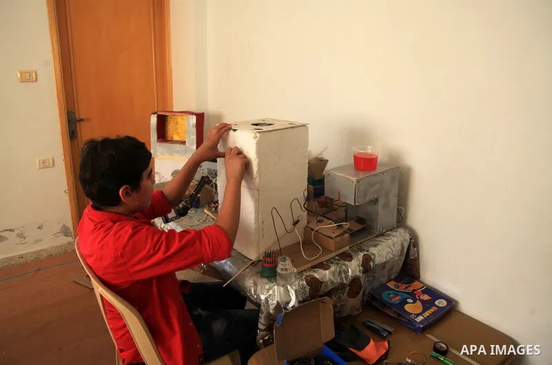 Palestinian inventor Mohammad Al-Hallaq,13, displays his small inventions at his home in Khan Yunis, in the southern Gaza Strip, on October 23, 2021. Al-Hallaq invented the robot for special needs and portable refrigerat...