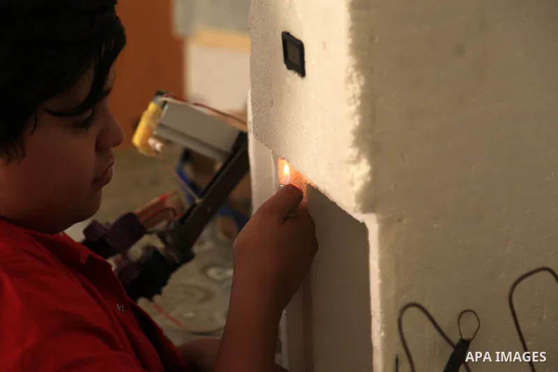 Palestinian inventor Mohammad Al-Hallaq,13, displays his small inventions at his home in Khan Yunis, in the southern Gaza Strip, on October 23, 2021. Al-Hallaq invented the robot for special needs and portable refrigerat...